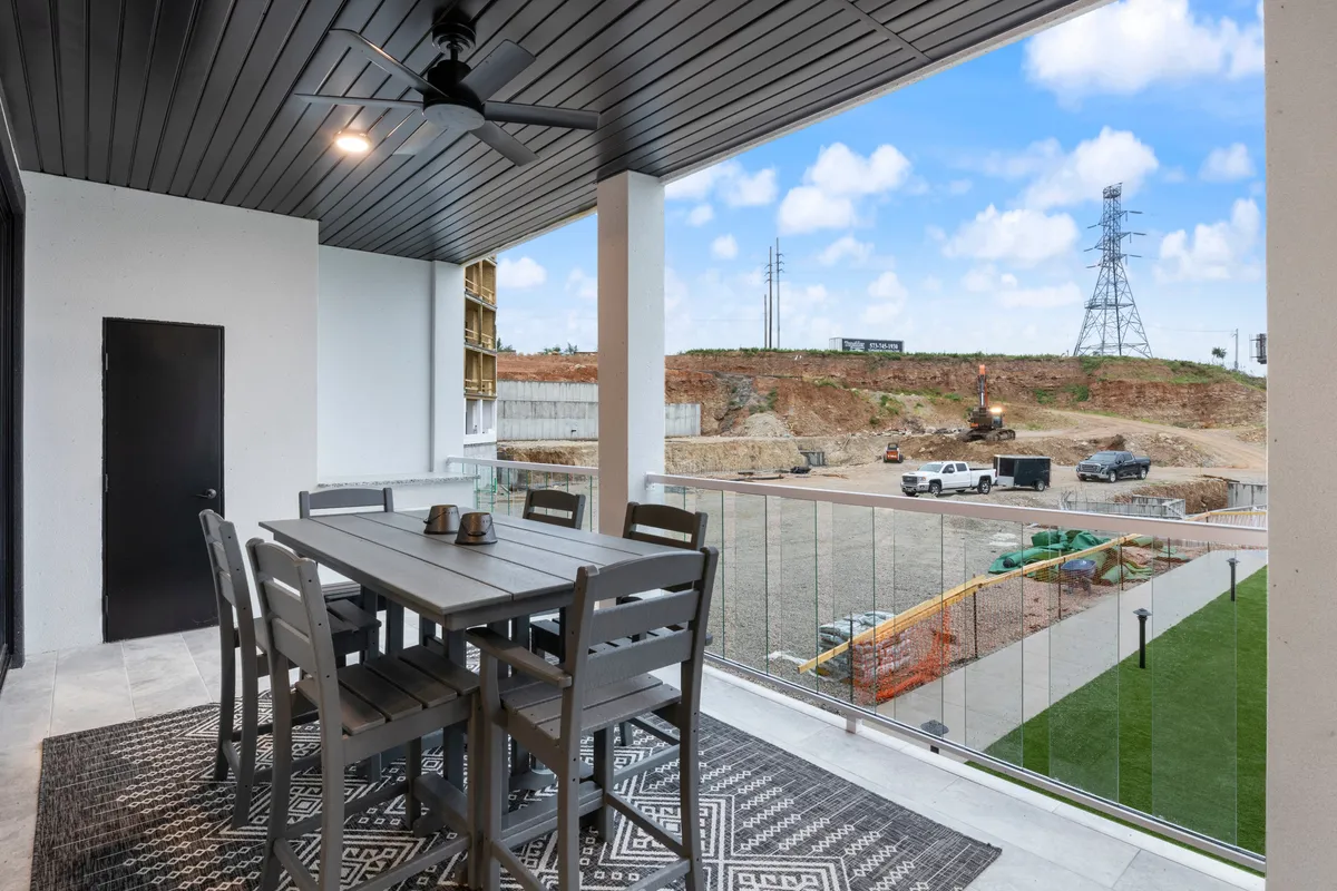 A spacious outdoor patio with a dining table set under an outdoor ceiling fan, surrounded by lush landscape. The table is perfectly positioned to enjoy open views, making it ideal for al fresco dining or relaxing with a morning coffee. The atmosphere is casual, comfortable, and inviting, reinforcing the sense of a private outdoor retreat.