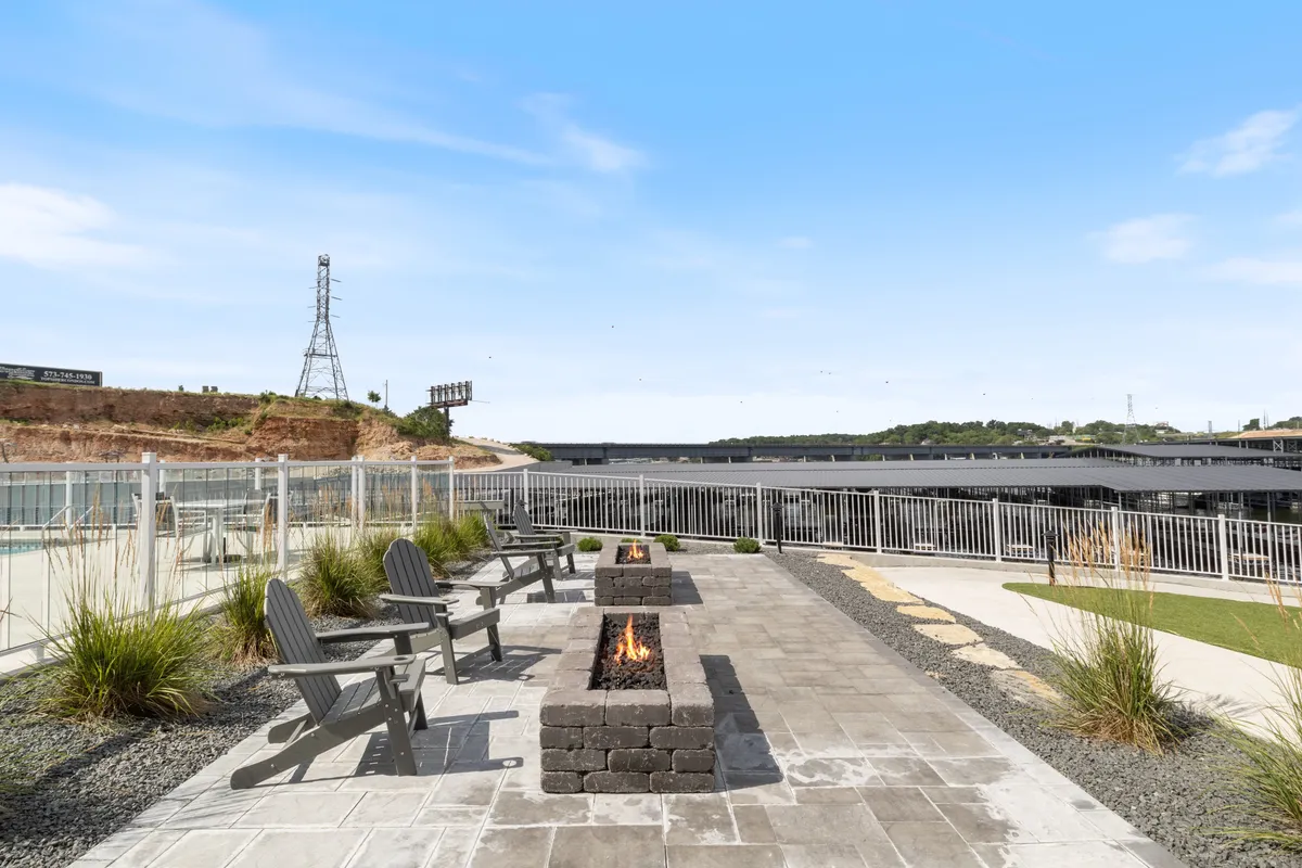 An inviting fire pit encircled by Adirondack chairs, set against a scenic landscape view. The area is designed for cozy evening gatherings, with the comfort of the fire and open sky enhancing the experience of lakeside living.