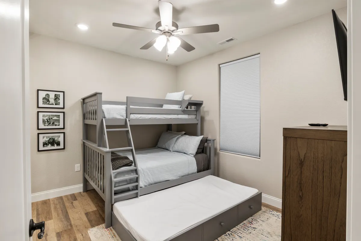A cozy bedroom with a bunk bed, a sturdy dresser, and framed photos on the wall. The space is welcoming and functional, perfect for families or children, and well-suited for amenities like a pack n' play or bedtime routines for little ones.